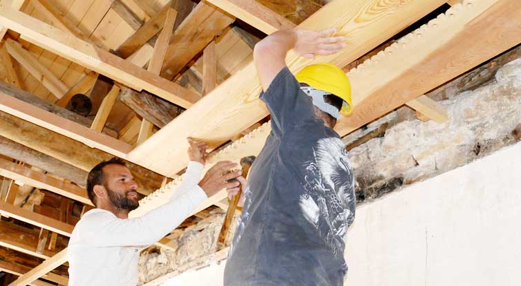 Carpenters work on traditional ceiling panels.